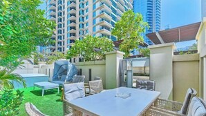 A patio area with outdoor furniture, a pool, and a view of high-rise buildings.