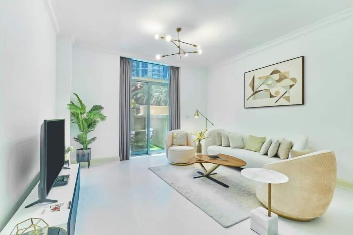 Ein modernes Wohnzimmer mit Flachbildfernseher, Sofa, Couchtisch und Stehlampe.