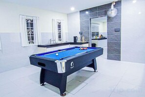 A pool table in a room with a modern design, a kitchen area, and a bathroom with a mirror. - Modern 5-Bedroom House BBQ Event Wedding at Kajang by HCK (Kajang)