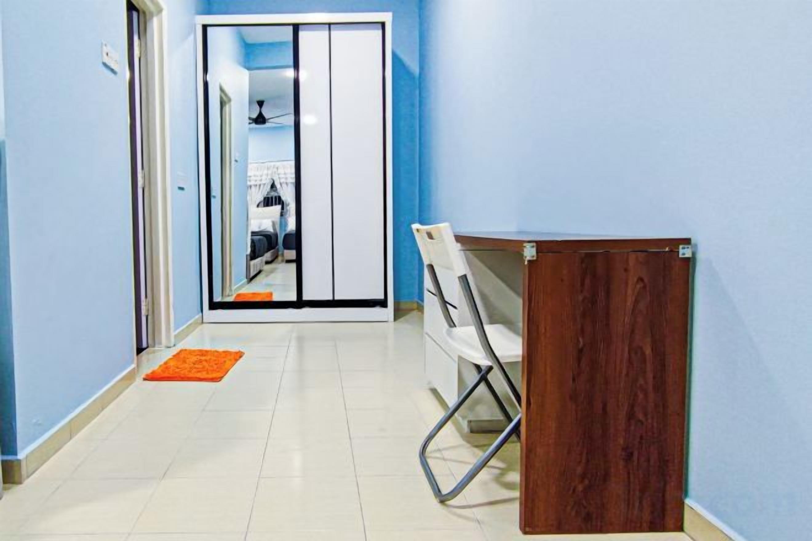 Un pasillo con un escritorio de madera, una silla blanca y una puerta que da a una habitación.