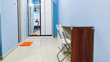 Un pasillo con un escritorio de madera, una silla blanca y una puerta que da a una habitación.