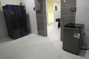 A hallway with a refrigerator, a trash bin, and a door leading to another room. - Modern 5-Bedroom House BBQ Event Wedding at Kajang by HCK (Kajang)
