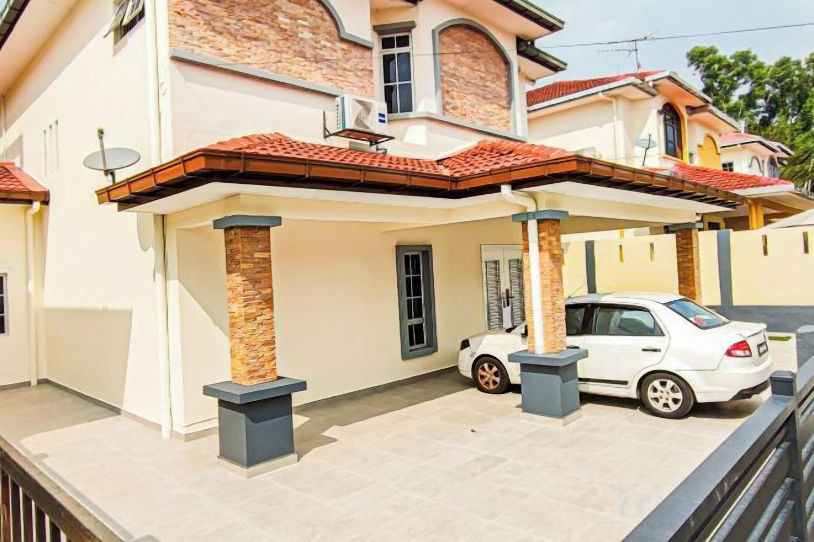 A two-story house with a covered patio area, a white car parked in front, and a satellite dish on the roof.