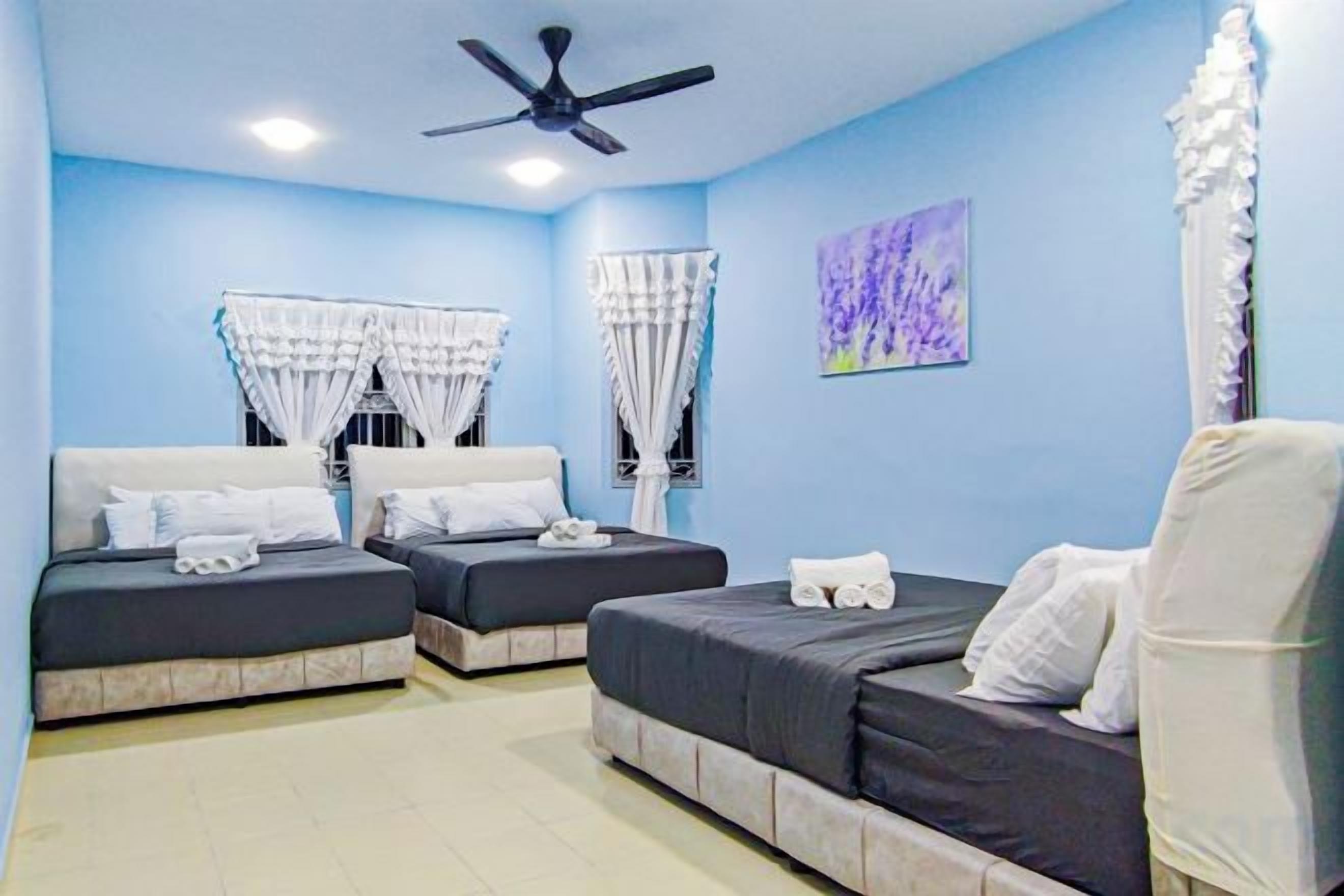 Habitación de hotel con dos camas, ventilador de techo y un cuadro en la pared.