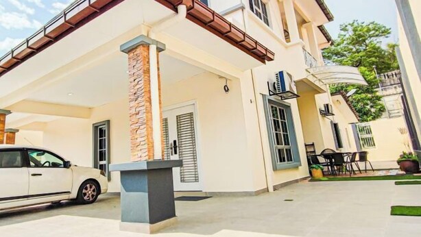 A modern two-story house with a covered patio, a car parked in the driveway, and a small outdoor seating area. - Modern 5-Bedroom House BBQ Event Wedding at Kajang by HCK (Kajang)