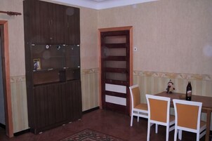 Een kamer met een houten kast, een eettafel met stoelen en een kamerbreed tapijt.