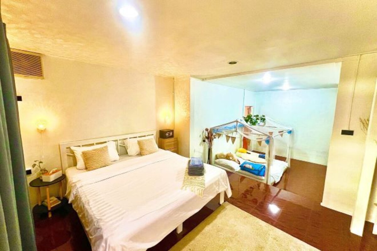 Une chambre d’hôtel comprenant un lit, une table de chevet, une lampe et un petit coin salon avec une table et des chaises.