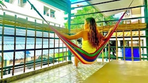 Una persona descansando en una hamaca junto a una ventana con vistas al agua.