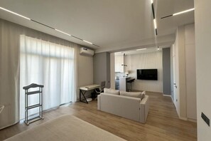 A modern living room with a sofa, a desk, and a television. - Minor River apartments (Tashkent)