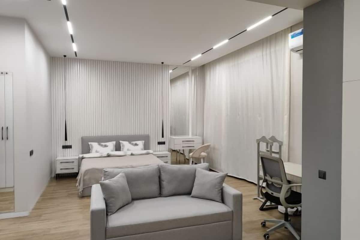 Une chambre à coucher moderne avec un lit, des tables de chevet, un bureau et une chaise.