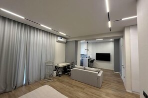 A modern living room with a sofa, a dining table, and a kitchen area in the background. - Minor River apartments (Tashkent)