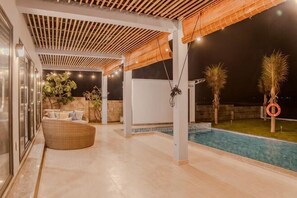 A covered outdoor area with a pool, a wicker chair, and a lifebuoy. - MyGarden Villa Phan Thiet Beachfront (Phan Thiet)