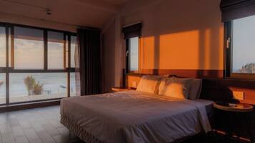 A bedroom with a large bed, a nightstand, and a view through a window.