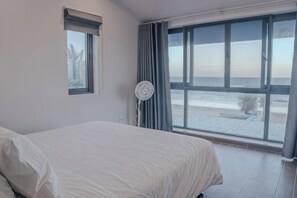 A bedroom with a bed, a window with a view of the beach, and a ceiling fan. - MyGarden Villa Phan Thiet Beachfront (Phan Thiet)