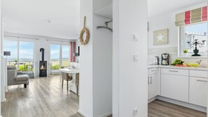 A spacious living area with a fireplace, a dining table, and a view of the sea. - Vacation home Bellevue directly on the Schlei with fireplace, sauna and whirlpool (Kappeln)