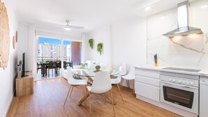 Una cocina moderna con armarios blancos, una campana extractora de acero inoxidable y un horno empotrado.