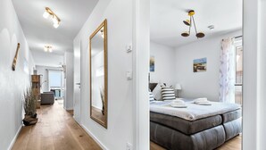 A modern bedroom with a large bed, a mirror, and a view of the outdoors. - Vacation apartment Moby Dick OstseeResort Olpenitz - sea view, balcony & harbor flair (Kappeln)