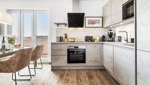 Een moderne keuken met een ingebouwde oven, een koffieapparaat en een magnetron. Er is een eethoek met een tafel en stoelen.