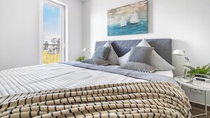 Een slaapkamer met een bed, een schilderij, een nachtkastje en een raam.