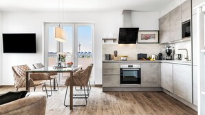 Een moderne keuken met een eethoek, met een groot raam, een flatscreen televisie en uitzicht op een vuurtoren.
