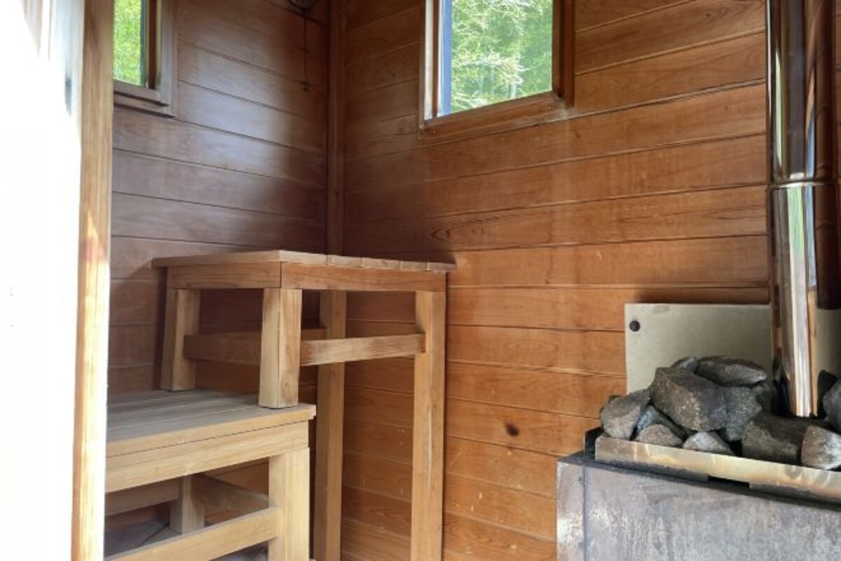 A wooden cabin interior with a wooden table, a fireplace, and a window.