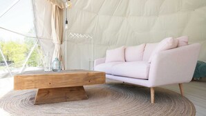 A modern interior with a light pink sofa, a wooden coffee table, and a hanging light fixture.