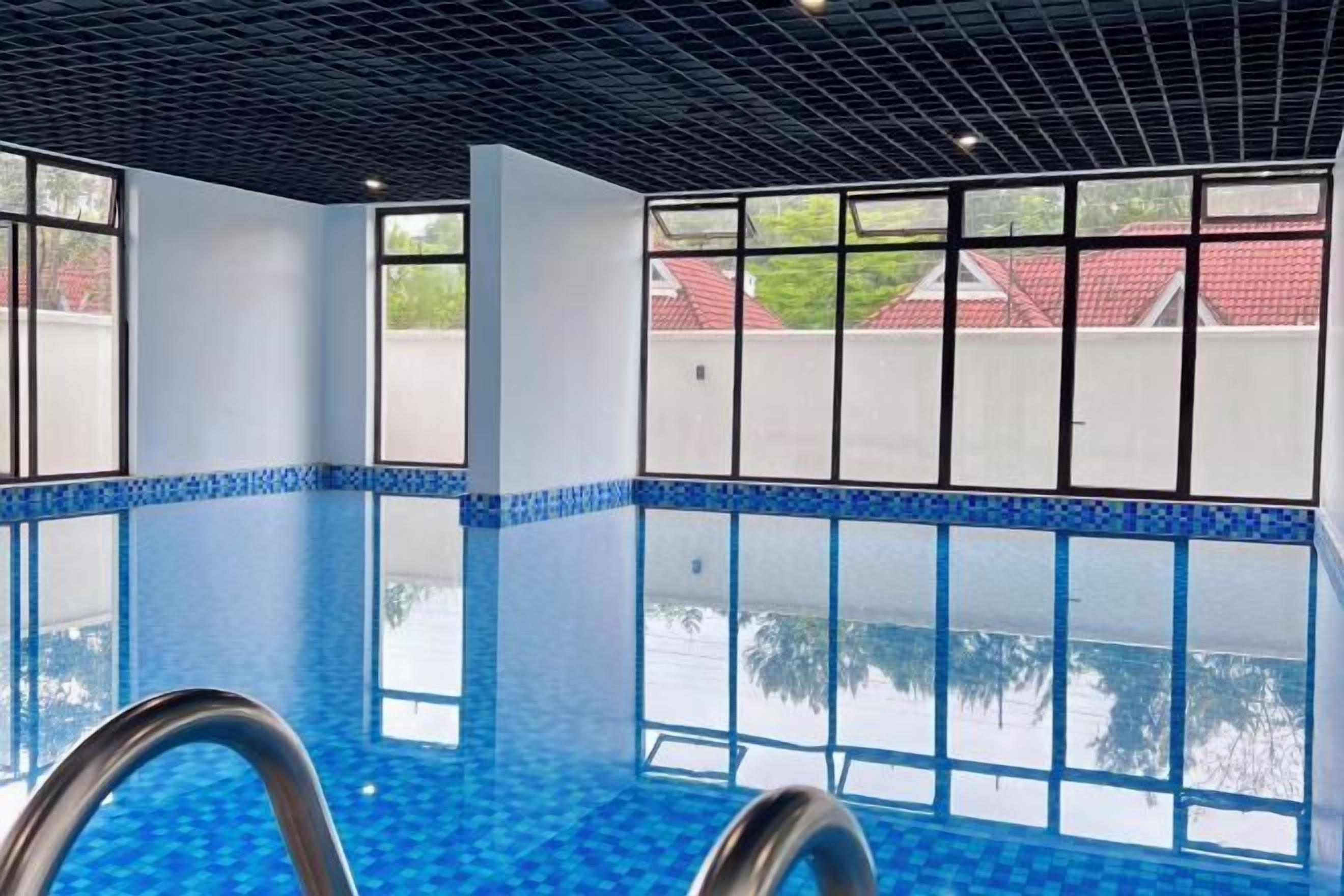 Ein Innenpool mit klarem, blauem Wasser, großen Fenstern und einem modernen Deckenbau.