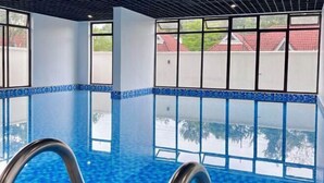 An indoor swimming pool with clear blue water, large windows, and a modern ceiling design. - Modern 1Br, Queen, Gym, Pool,Central in Kileleshwa (Nairobi)