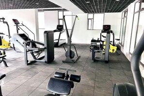 A gym with various exercise equipment, including weight machines and cardio machines. - Modern 1Br, Queen, Gym, Pool,Central in Kileleshwa (Nairobi)