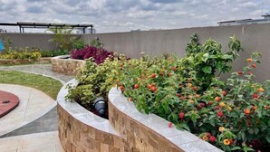 A rooftop garden with various plants and a curved stone wall. - Modern 1Br, Queen, Gym, Pool,Central in Kileleshwa (Nairobi)