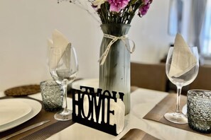 A dining table with a vase of flowers, a sign reading 'HOME,' and two wine glasses. - Modern 1Br, Queen, Gym, Pool,Central in Kileleshwa (Nairobi)