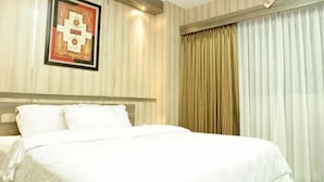 A hotel room with a bed, a framed artwork on the wall, and a window with curtains. - Graha Sumsel Jakarta (Central Jakarta)