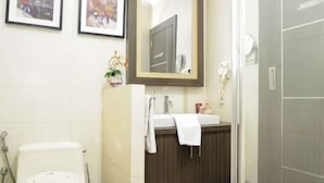 A bathroom with a toilet, sink, mirror, and shower. - Graha Sumsel Jakarta (Central Jakarta)