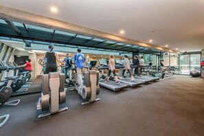 Une salle de sport équipée de tapis de course, d’appareils elliptiques et de vélos d’appartement.
