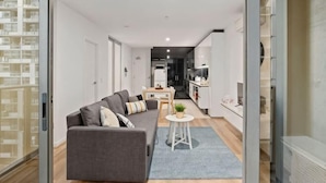 A modern apartment with a living area, kitchenette, and a view of the city. - Charming 2BR Apartment with Free Parking (Melbourne)