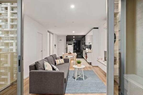 A modern apartment with a living area, kitchenette, and a view of the city. - Charming 2BR Apartment with Free Parking (Melbourne)
