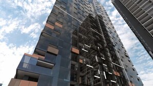 A high-rise building with multiple floors, large windows, and a modern architectural design. - Charming 2BR Apartment with Free Parking (Melbourne)