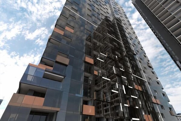 A high-rise building with multiple floors, large windows, and a modern architectural design. - Charming 2BR Apartment with Free Parking (Melbourne)