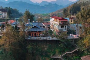 Un pueblo montañoso con casas tradicionales, un edificio destacado de techo rojo y un pequeño templo.