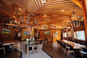 Un interior espacioso de madera con techos altos, candelabros y varias mesas de comedor.