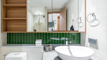 A modern bathroom with a large mirror, a white sink, and a shower.