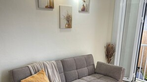 A modern living room with a grey sofa, a glass coffee table, and a woven rug. - House located 100 meters from one of the Caribbean's most beautiful beaches (Sainte-Anne)