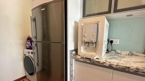 A compact kitchen with a stainless steel refrigerator, a washing machine, and a built-in microwave. - Cozy Straits Quay Seafront Homestay (Tanjung Tokong)