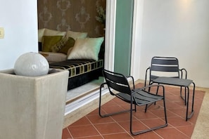 A room with a bed, two chairs, a white vase, and a patterned wall. - Cozy Straits Quay Seafront Homestay (Tanjung Tokong)