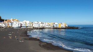 A coastal town with colorful buildings along the beach, a sandy shoreline, and calm sea.