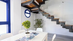 A modern interior with a white table, potted plants, and a staircase.