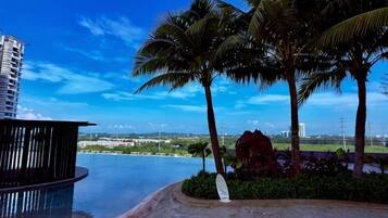 Área de piscina com vista para a paisagem urbana, palmeiras e um edifício moderno.