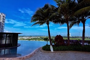 Zona de piscina con vistas a un paisaje urbano, palmeras y un edificio moderno.