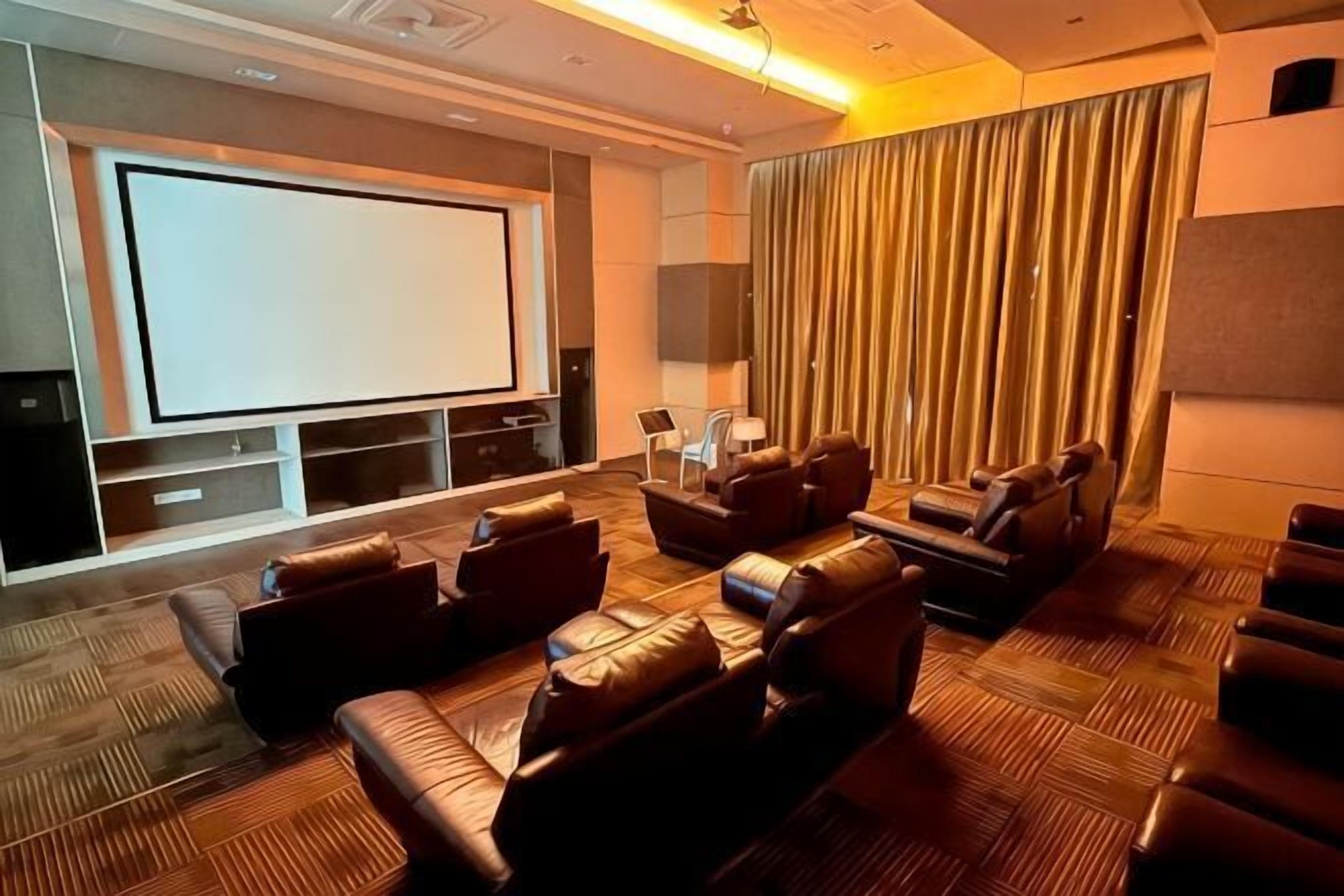 A home theater with a large screen, leather seating, and a patterned carpet.