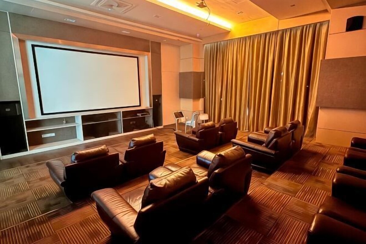 A home theater with a large screen, leather seating, and a patterned carpet.